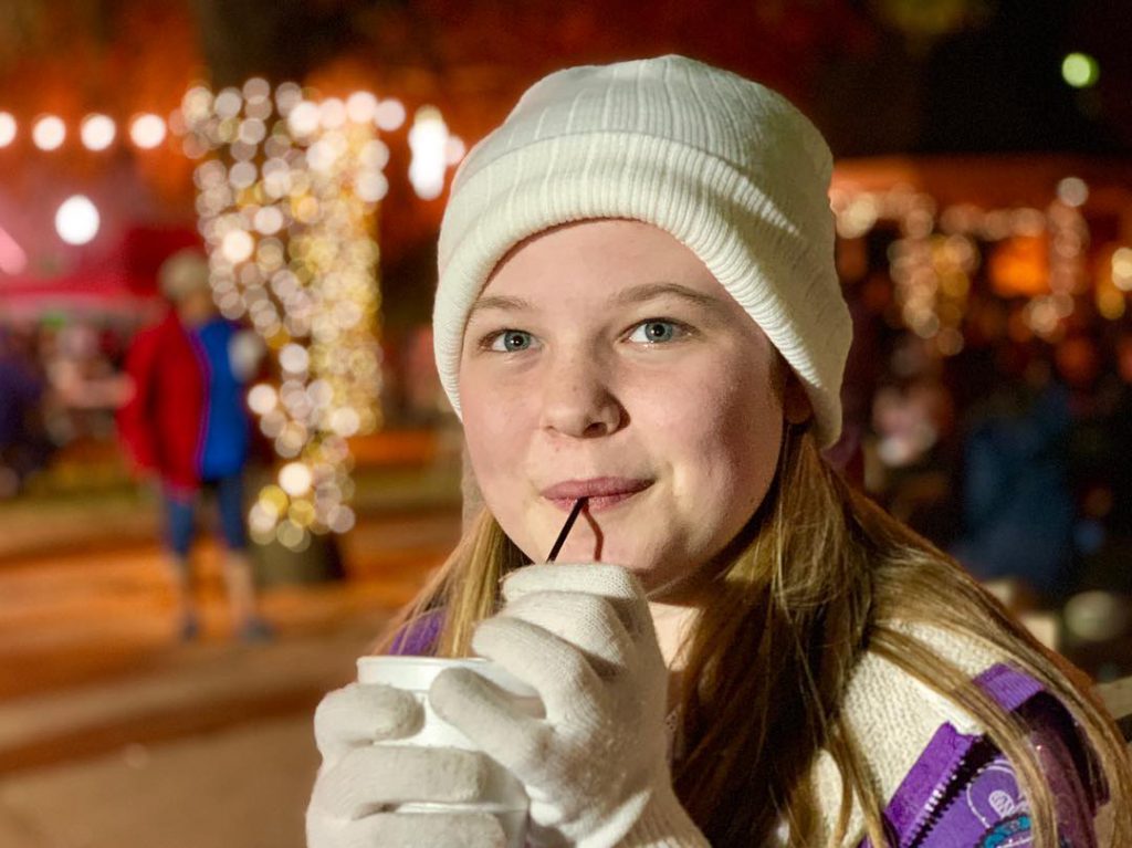 Girl drinking hot chocolate wearing gloves and beanie