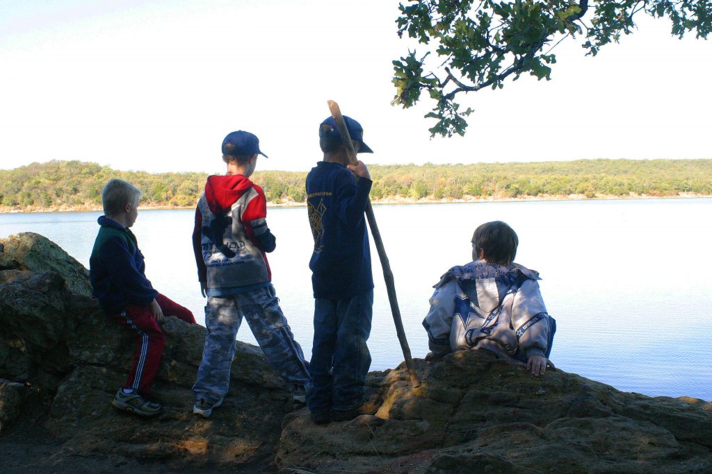Four boys looking out at lake from shore