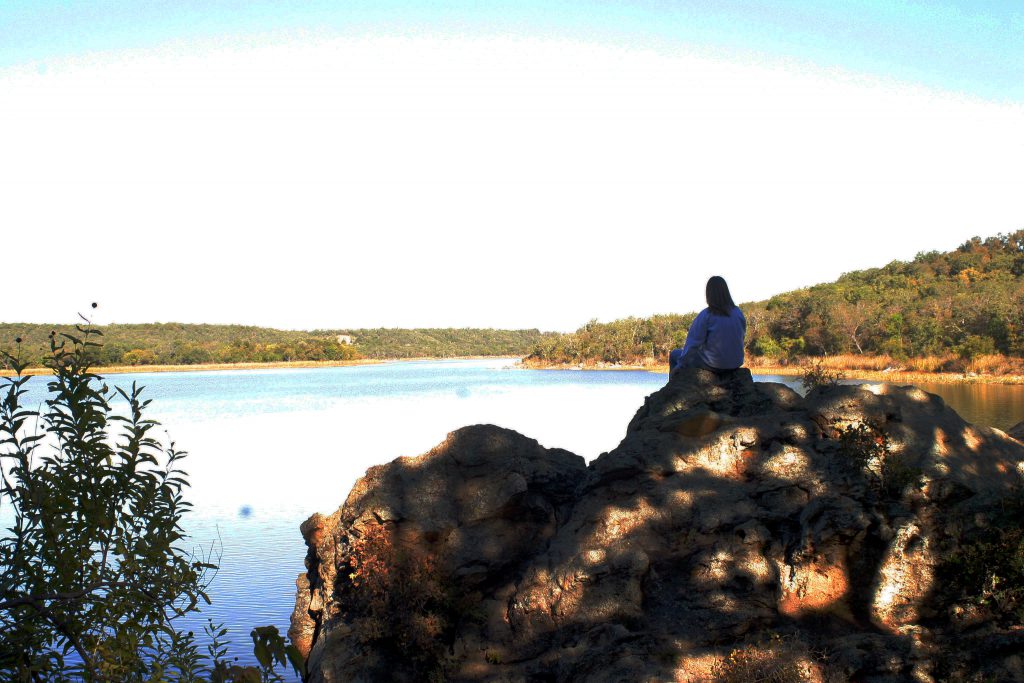 Woman sitting on rocks at lake shore
