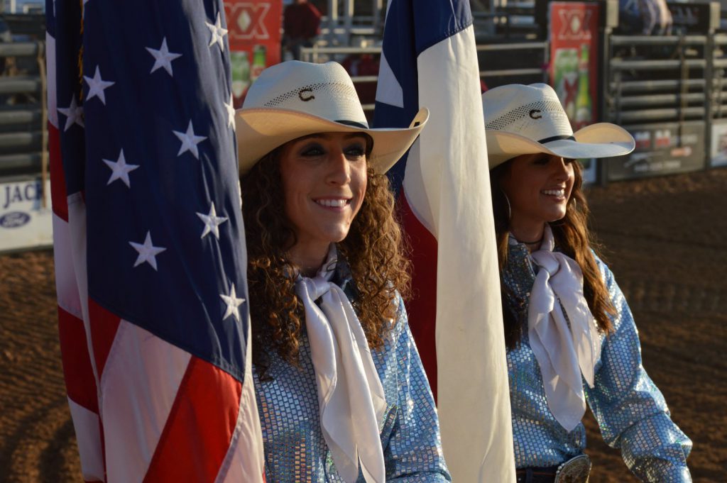 Girls carrying flags at rodeo