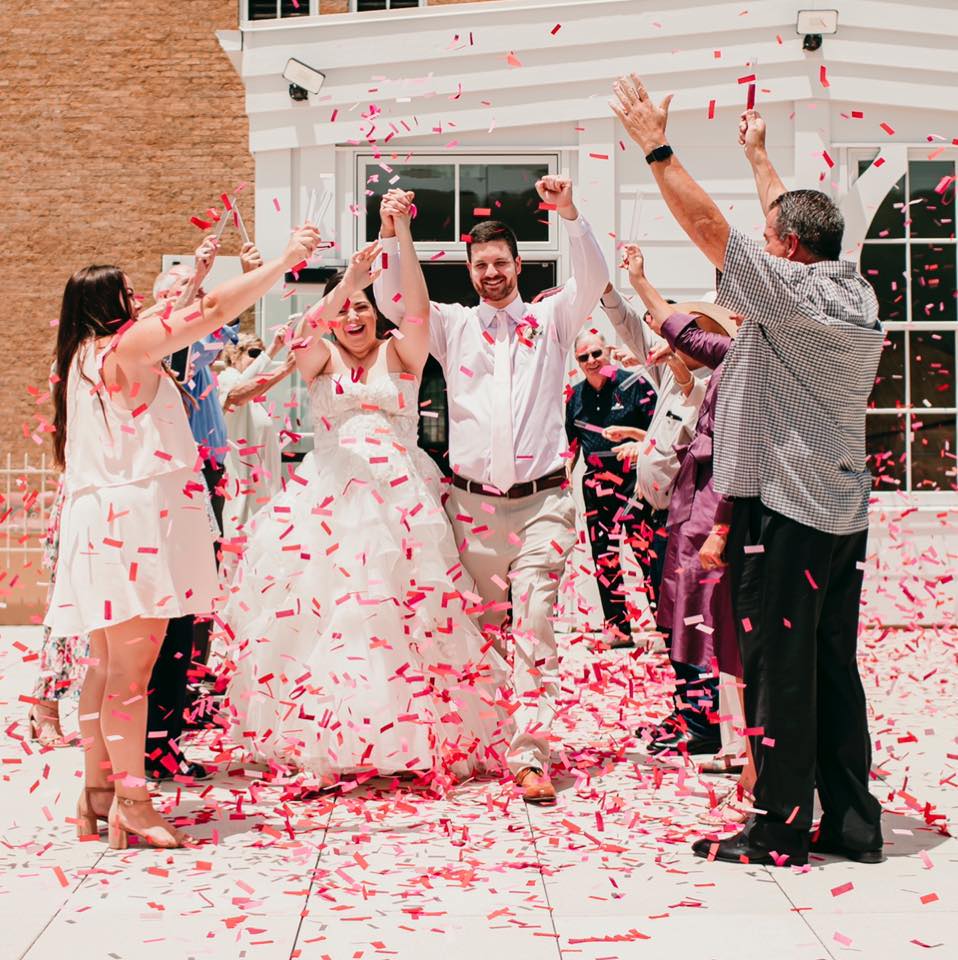 Wedding party throwing confetti on bride and groom
