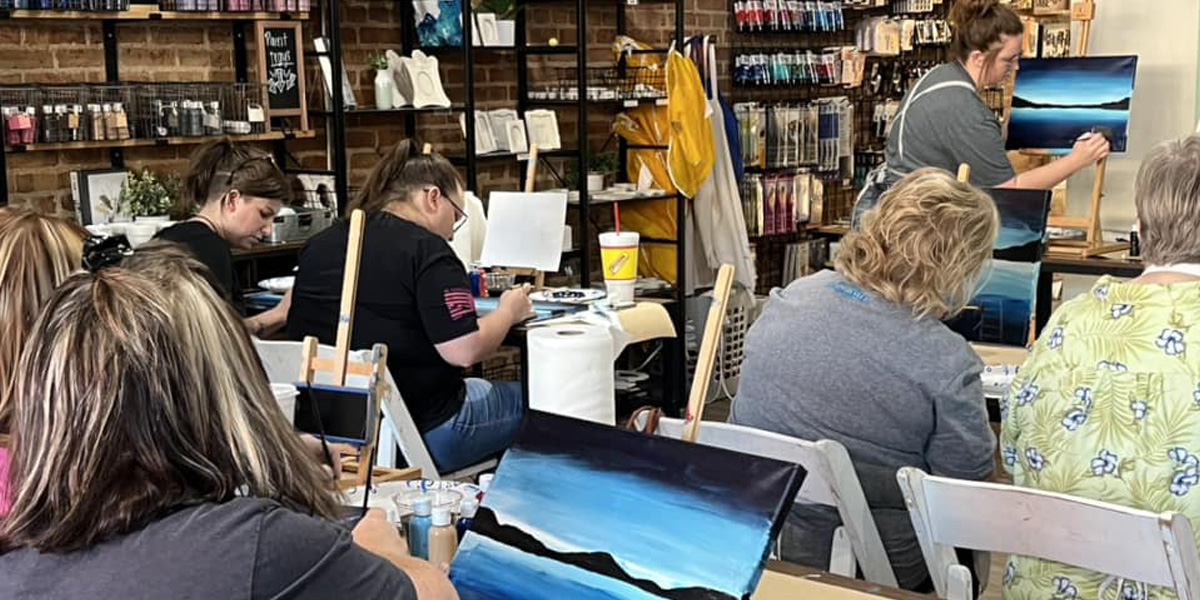 participants learning hout to paint in a class with instructor