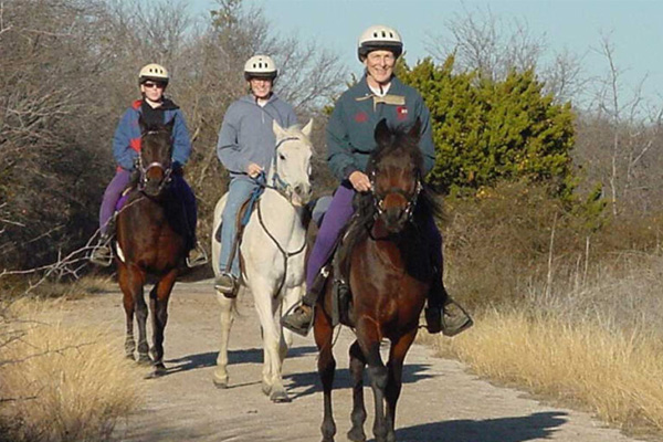 3 people riding horses on trail