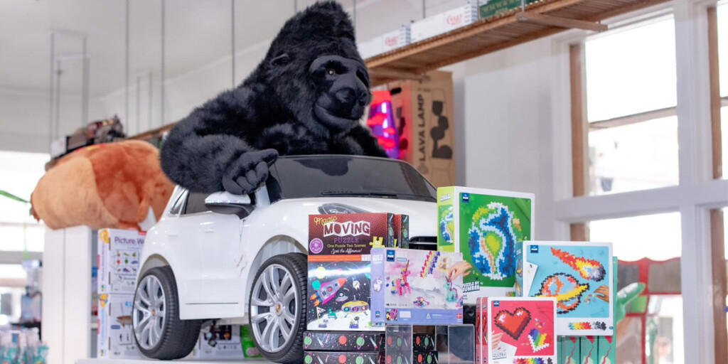 Gorilla siting in toy Porsche in a a toy shop